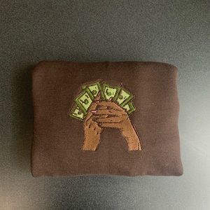Embroidered crewneck brown skin hands hold money